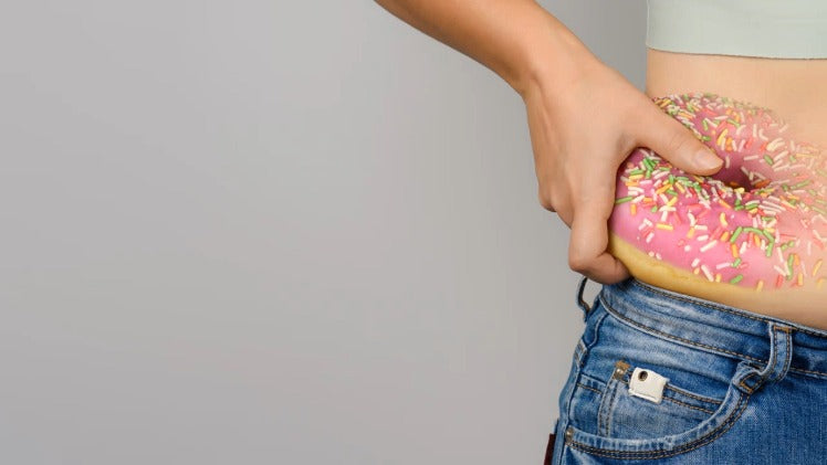 Womans waist with a fat as a donut on her belly. Overweight concept