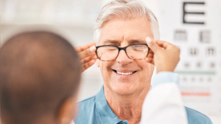 optometrist with elderly man fitting glasses